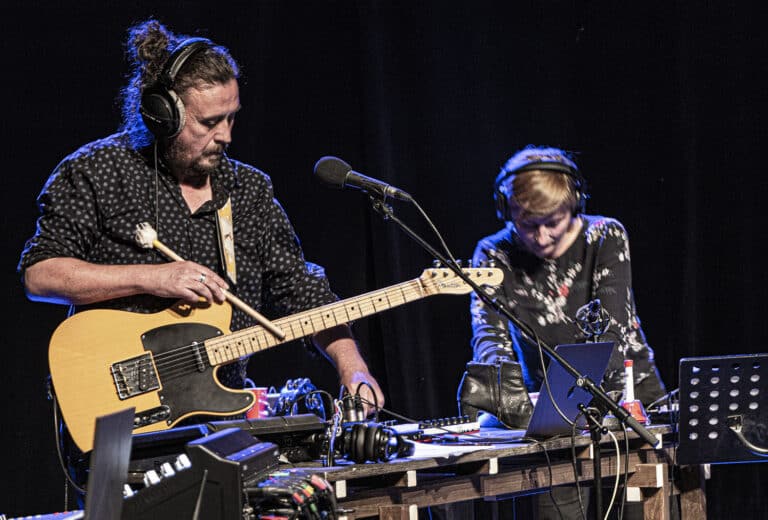 La compagnie Intermezzo en train de travailler sur scène avec gros plan sur le guitariste et la comédienne qui manipule une console de son