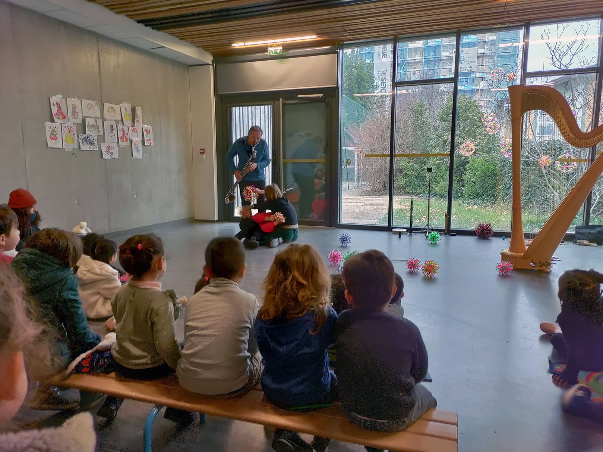 Une danseuse, une harpiste et un saxophoniste montre un extrait de leur spectacle à des enfants dans une classe